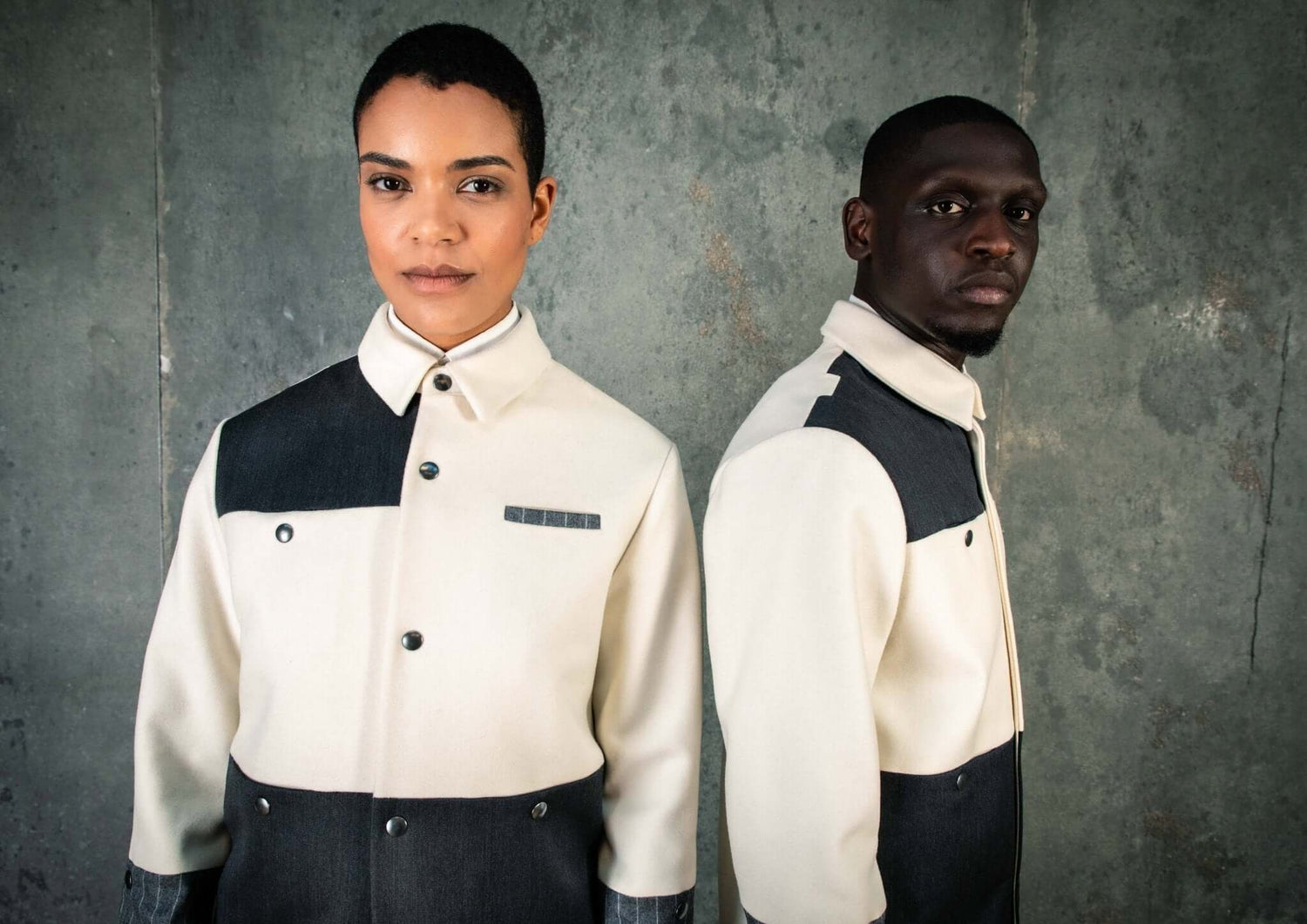 LA VESTE COACH BLANCHE & GRISE EN LAINE & CACHEMIRE portée par un modèle dans un décor industriel.