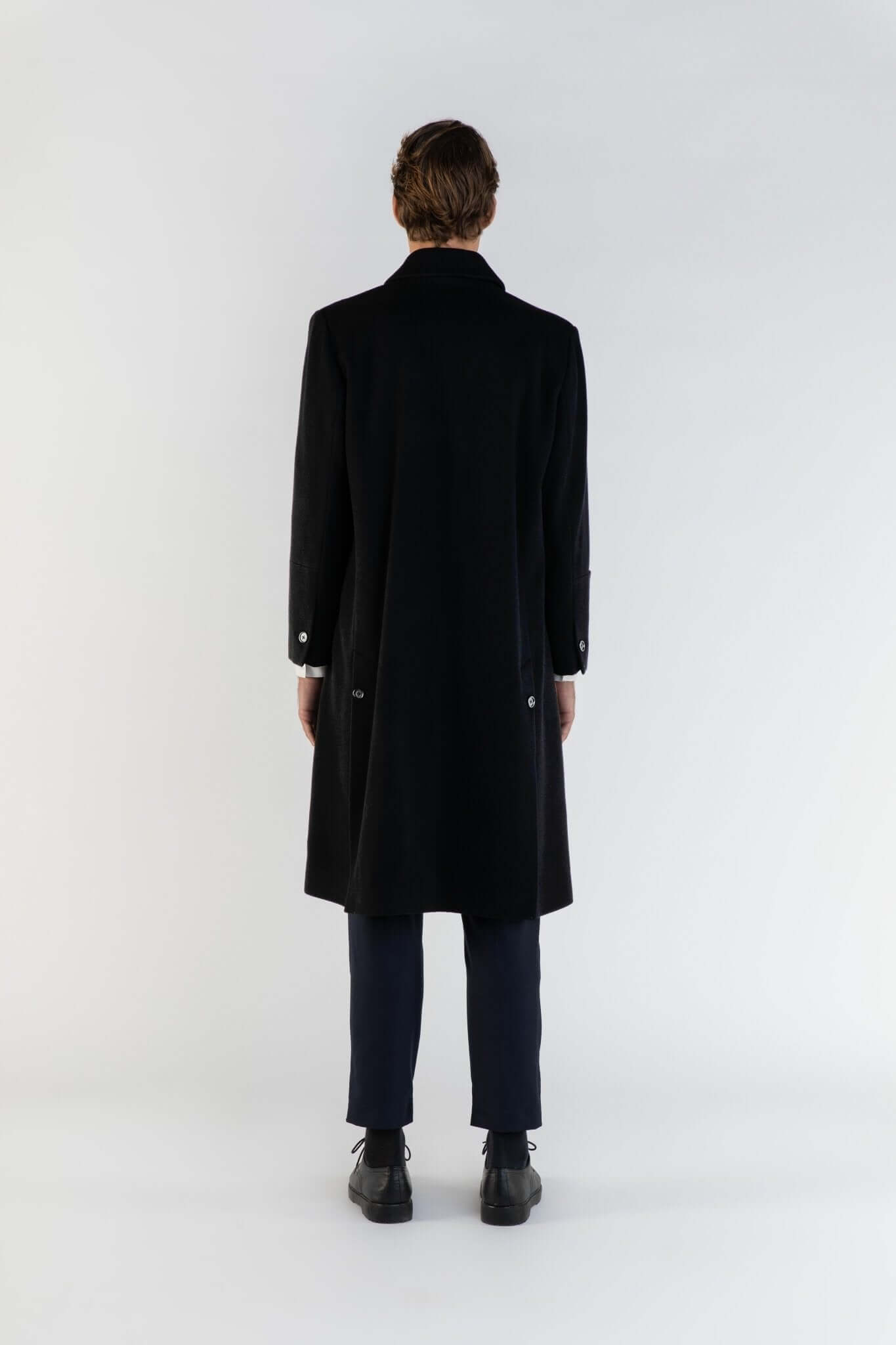 Homme portant LE MANTEAU NOIR EN LAINE & CACHEMIRE, vu de dos, mettant en valeur son élégance et sa fabrication française.