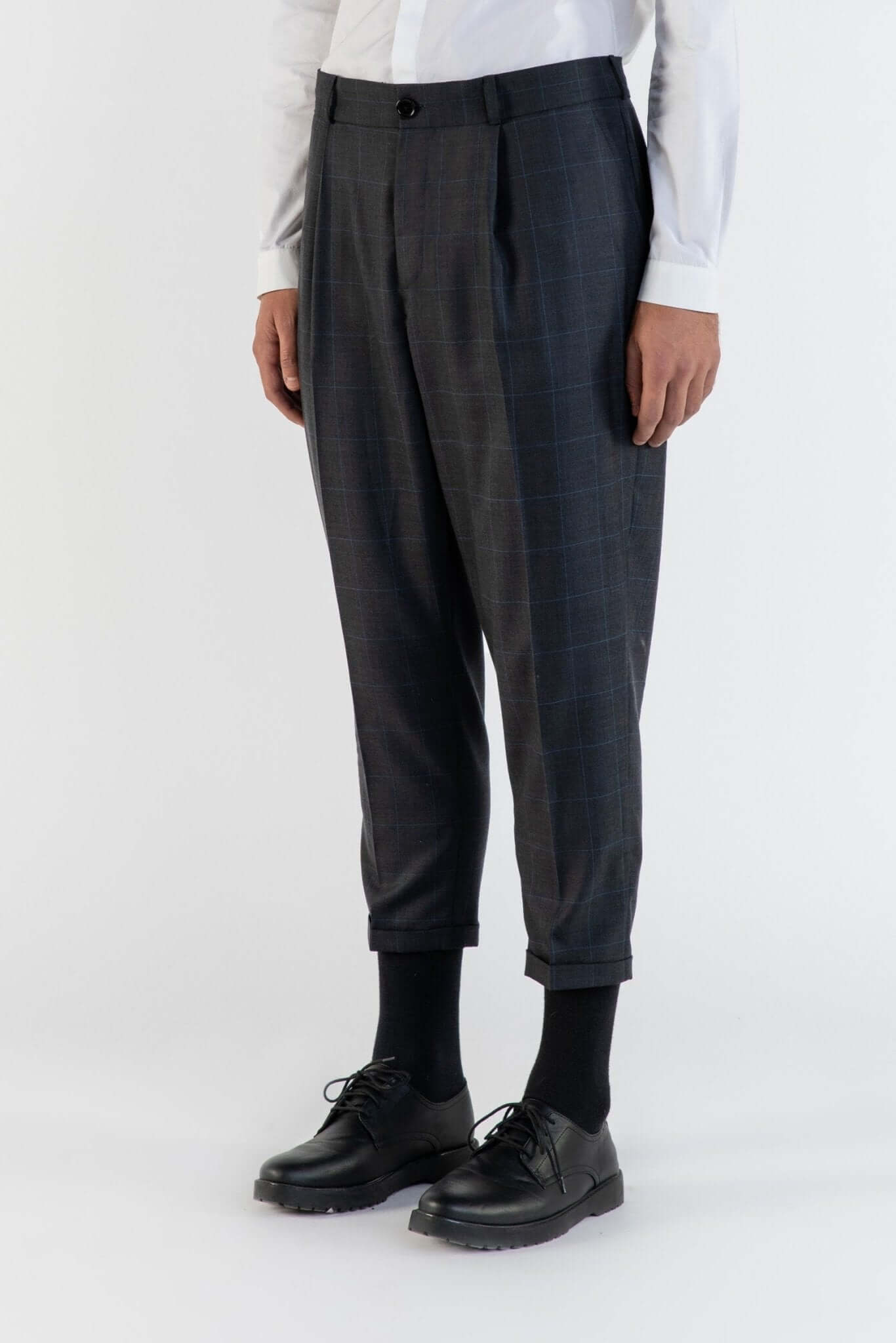 LE PANTALON MARRON À PLIS EN LAINE porté avec une chemise blanche, présentant un style moderne et élégant.