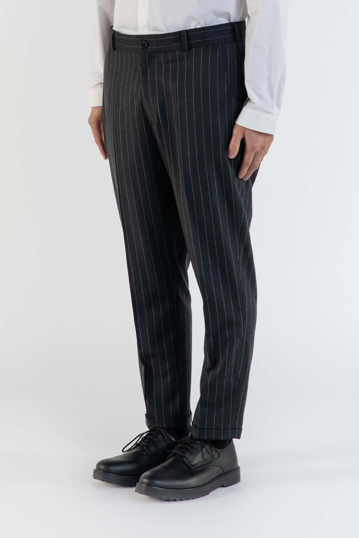 LE PANTALON GRIS À RAYURE EN LAINE porté avec une chemise blanche et des chaussures noires.