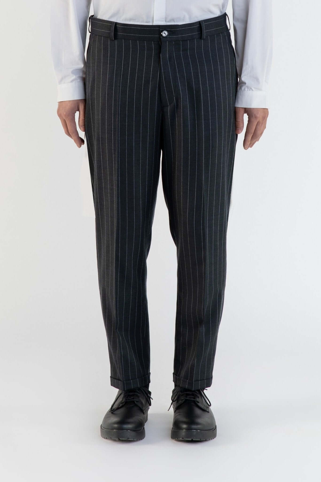LE PANTALON GRIS À RAYURE EN LAINE porté par un homme, avec des rayures élégantes sur un tissu de qualité.