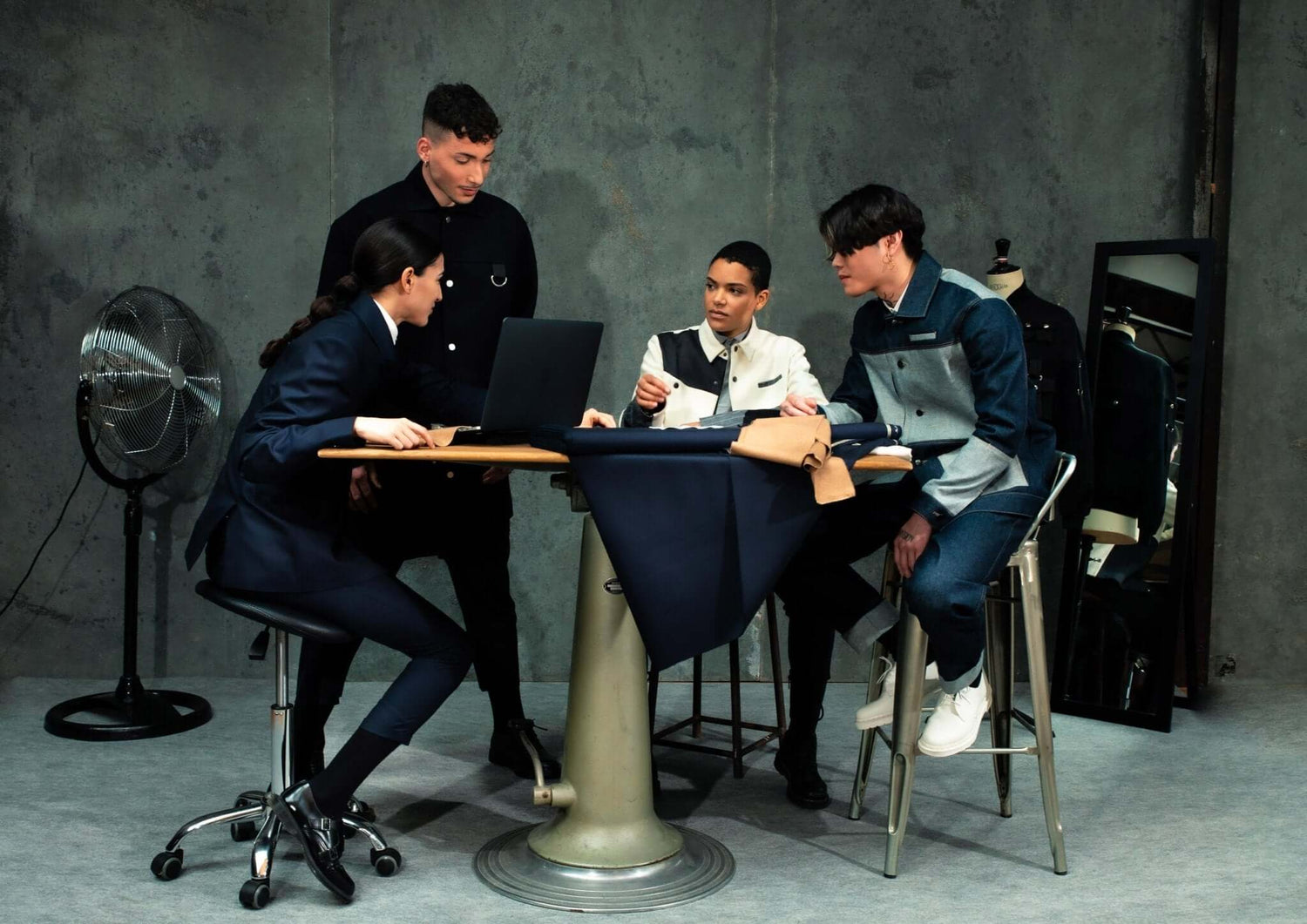 LA VESTE WORKER BLEUE EN COTON worn by a group of four young adults collaborating at a table.
