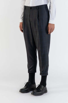 LE PANTALON MARRON À PLIS EN LAINE porté avec une chemise blanche, présentant un style moderne et élégant.